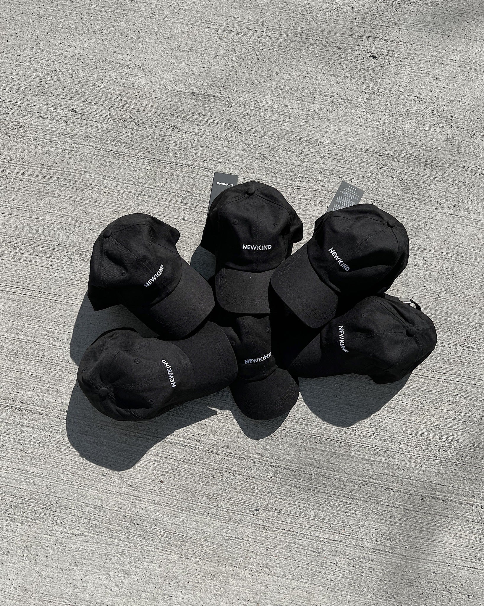 Newkind baseball cap in black. The cap features Newkind branding throughout and a metal clip fastening at the back. - Embroidery logo - 6 Panel baseball cap - Composition: 100% cotton