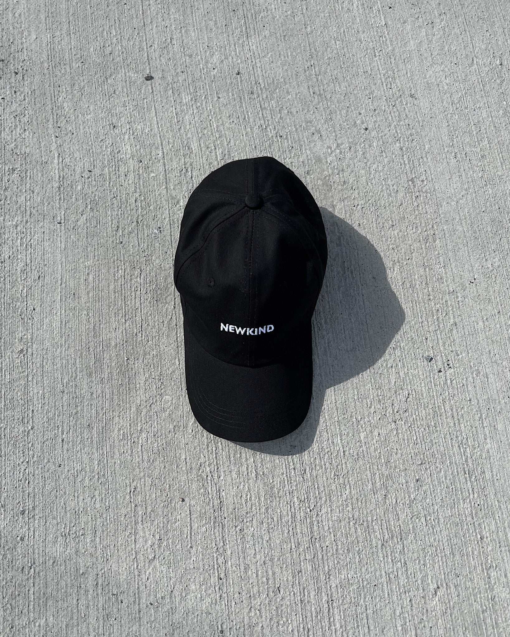 Newkind baseball cap in black. The cap features Newkind branding throughout and a metal clip fastening at the back.  - Embroidery logo  - 6 Panel baseball cap    - Composition: 100% cotton